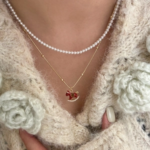18K gold plated pearl necklace with a red rocking horse pendant on a beige knit sweater