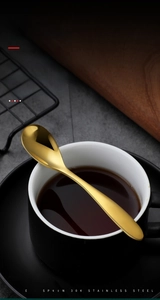 Macro shot of 304 stainless steel gold coffee spoon resting on a black ceramic cup