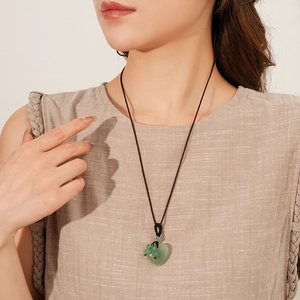 Detail of green jade heart pendant on brown woven rope worn by a model