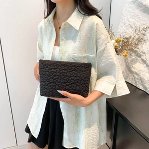 Minimalist black quilted flower clutch bag with three-dimensional floral texture
