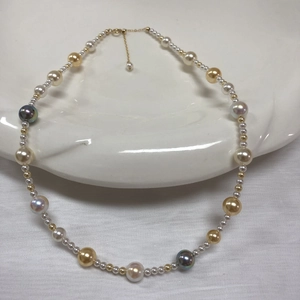 Detailed macro view of multi-color pearls with golden clasp on white ceramic tray