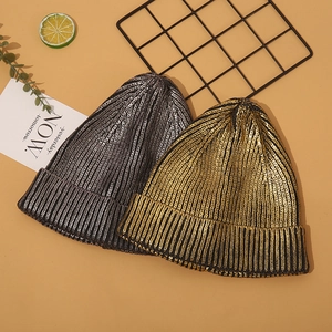 Detail of metallic gold and silver knitted beanies with shiny vertical ribbed texture