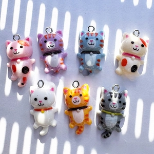 Close-up of seven assorted colorful resin cartoon cat pendants with metal rings for DIY jewelry