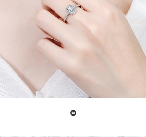 Detailed close-up of emerald-cut zircon ring with halo setting on a female hand