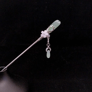 Detailed macro view of vintage silver hair pin with green jade plum blossom pendants