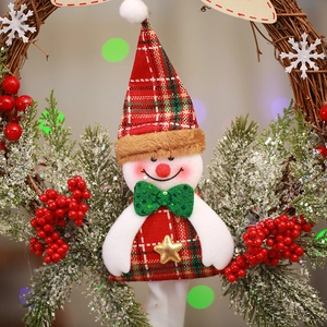 Close-up of a Christmas wreath featuring a snowman doll with pine needles and red berries