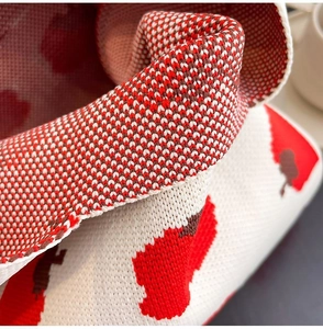 Close-up of soft knitted fabric texture with red and brown floral patterns on cream tote