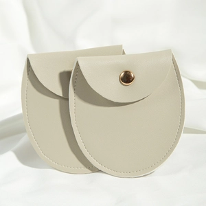 Macro shot of two round beige PU leather jewelry pouches with golden metal snap closures