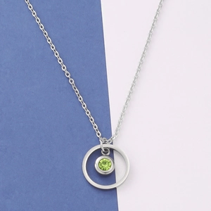 Macro view of silver geometric necklace with green birthstone pendant on blue background