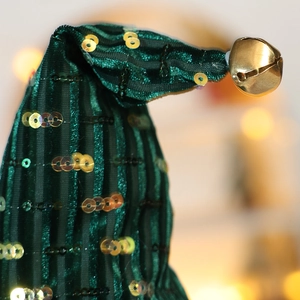 Macro shot of green Christmas elf hat featuring gold sequins and a metallic bell detail