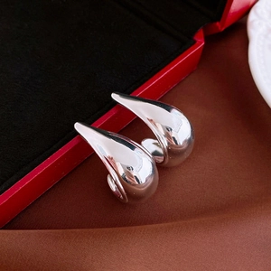 Detailed view of silver polished teardrop stud earrings on a luxury jewelry box display