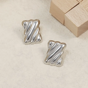 Polished silver geometric wave earrings in stainless steel on a minimalist background