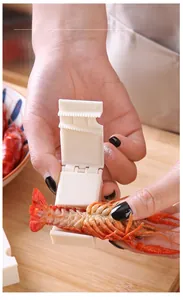 Detail of white plastic lobster peeler separating shell from meat on a wooden board