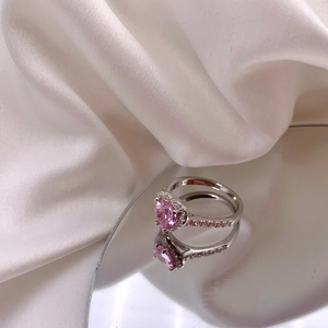 Macro detail of S925 silver ring featuring a pink heart gem on a reflective mirror