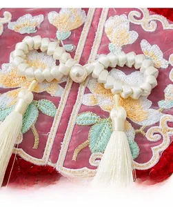 Detail showing traditional Chinese embroidery button with pearl and tassel on red fabric