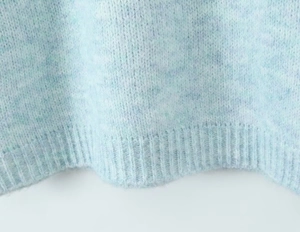 Close-up of light blue mohair knit sweater featuring ribbed hem and fuzzy texture details
