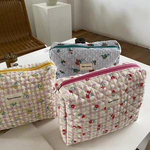 Three quilted makeup bags with floral patterns and checkered fabric on a table