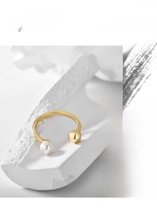 Detailed shot of golden open ring with white pearl and metal ball on stone base