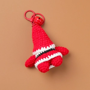 Handmade crochet Santa Claus keychain with red bell and buckle on warm brown background