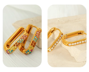 Close-up of geometric gold-plated rectangle hoop earrings with colorful and white crystals