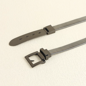 Detail of dark grey metal spring waist belt featuring a square buckle and punch holes