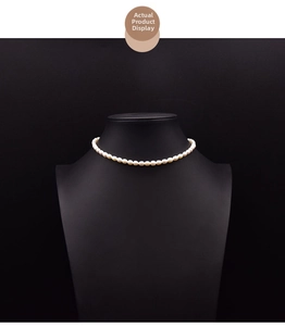 Detail view of natural white rice pearl necklace displayed on a black jewelry mannequin