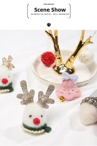 Detail of felt Christmas ornaments featuring a white reindeer head and pink bells on a tray