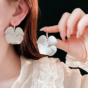 Elegant white matte layered flower earrings with gold hooks on model and in hand