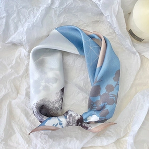 Close-up of luxury silk scarf with blue and grey pattern on textured white background