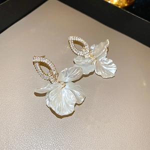 Detail of floral drop earrings with white textured petals and shimmering crystal studs