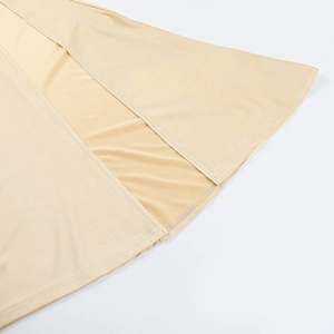 Gros plan détaillé montrant la couture de qualité et l'ourlet fendu de la robe beige
