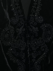Detailed view of black velvet vest with intricate floral embroidery and beadwork