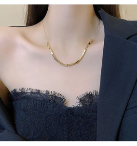 Detail of golden tube bead necklace worn by model for a minimalist chic choker look
