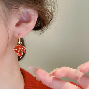 Gros plan de boucles d'oreilles feuilles d'érable rouges avec diamants portées par un mannequin