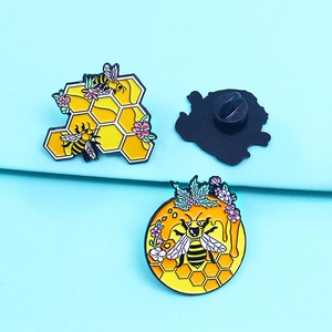 Set of three honey bee and honeycomb enamel pins on a light blue background surface