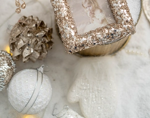 Detail of white knit glove and gold sequin ornaments with photo frame decor
