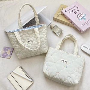 Detailed shot of quilted canvas handbags with floral patterns and bow embroidery