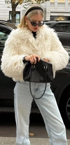 Close-up of white long-haired faux fur coat texture with stylish winter street outfit