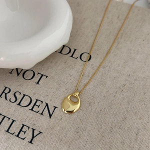 Macro shot of minimalist gold teardrop pendant with high polish finish and fine chain