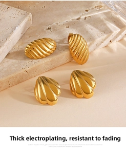 Detail of vintage gold plated geometric ear studs on beige travertine stone texture