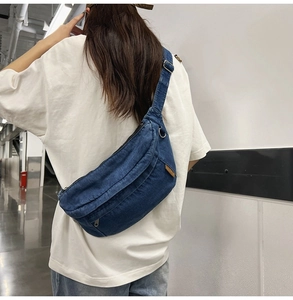 Blue denim crossbody chest bag with adjustable strap worn on model back in modern hallway