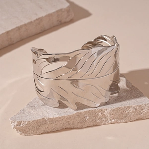 Détail du bracelet feuille argenté avec veines gravées posé sur une pierre texturée