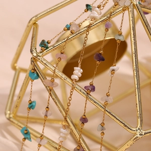 Detailed macro view of natural turquoise and amethyst stones on a gold-plated anklet chain