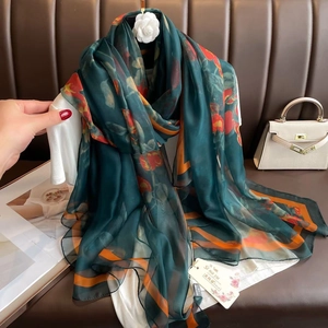 Detail of soft dark green chiffon scarf featuring vibrant orange floral borders and texture