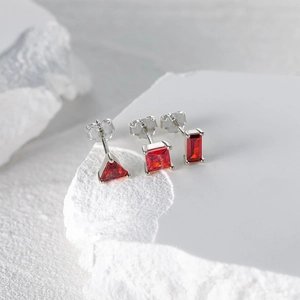 Macro shot of S925 silver studs with geometric red ruby stones on a marble block