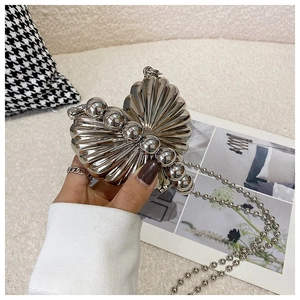 Detail of silver heart-shaped metal mini bag with large bead decor and chain strap