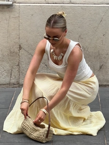 Summer yellow layered maxi skirt paired with straw handbag in a street style look