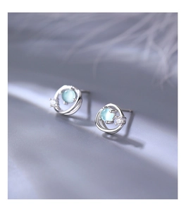 Detail of silver Saturn earrings with light blue glass bead and white zircon stones