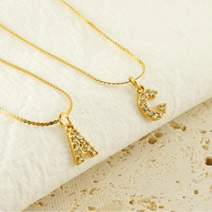 Gold stainless steel necklaces with crystal letter A and C pendants on stone surface