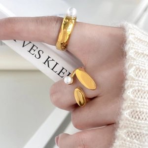 Detail shot of gold titanium steel pea-shaped rings with fresh water pearls on hand